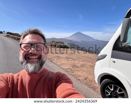 One adult man taking selfie picture outside a camper van motorhome parking in the mountain scenic view background. People and travel alternative lifestyle vanlife vacation renting vehicle. Leisure