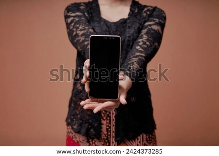 Close up picture of Indonesian woman in Kebaya showing mobile phone black screen