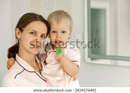 Portrait of Mother and daughter brushing teeth in the bathroom. Good morning concept. Daily routine and health care