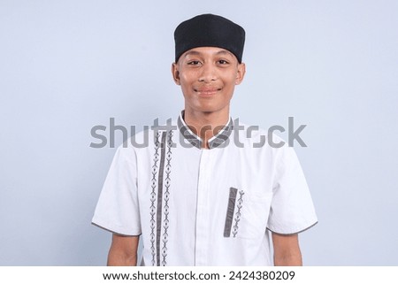 Portrait of smiling Asian muslim student man wear skullcap, looking at camera with happy expression
