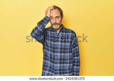 Caucasian middle-aged man in yellow studio tired and very sleepy keeping hand on head.