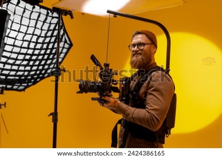 Professional videographer with camera equipment in studio. Royalty-Free Stock Photo #2424386165