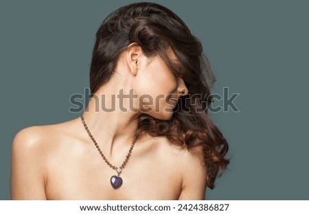 Healthy stylish brunette fashion model with makeup, wavy hairstyle and healthy clean skin posing on blue background. Portrait of jewelry woman in necklace
