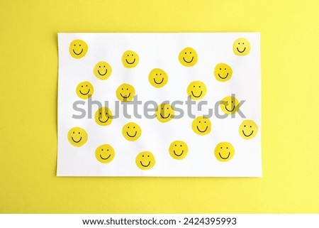 Many happy yellow smileys handpainted on white card on a bright yellow background - authentic image representing the concept of positive emotions, happiness, positive vibes, energy, motivation, fun