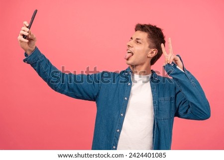 Young man taking selfie on pink background