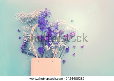 Top view image of violet delphinium flowers composition over blue background