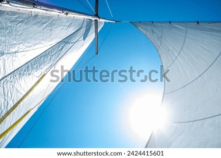 Mast of the boat bottom view, detail of sailboat, luxury water transport, summer holidays concept.  White sails of a sloop rigged yacht against blue sky. Rigging equipment close-up