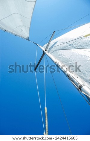 Mast of the boat bottom view, detail of sailboat, luxury water transport, summer holidays concept.  White sails of a sloop rigged yacht against blue sky. Rigging equipment close-up