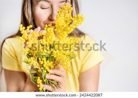 Beautiful young woman with mimosa flowers on white background. Close up Royalty-Free Stock Photo #2424422087