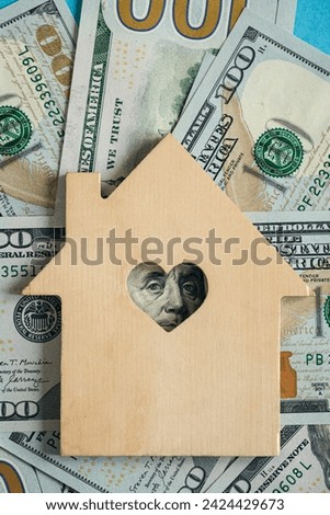 Wooden house model on background of US dollars banknotes. Housing market, purchase or rental of real estate. The concept of buying and selling real estate.