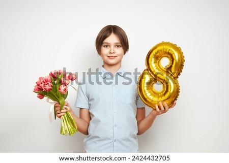 Cheerful happy child with Tulips bouquet and balloon number 8. Smiling boy on white background, rejoices spring holiday. Women's Day on March 8th