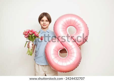 Cheerful happy child with Tulips bouquet and balloon number 8. Smiling boy on white background, rejoices spring holiday. Women's Day on March 8th