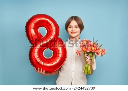 Cheerful happy child with Tulips bouquet and balloon number 8. Smiling boy on blue background, rejoices spring holiday. Women's Day on March 8th