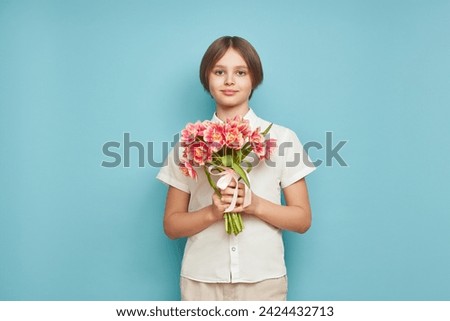 Cheerful happy child with Tulips bouquet. Smiling boy on blue background. Mother's Day. Love and romantic concept