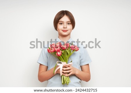 Cheerful happy child with Tulips bouquet. Smiling boy on white background. Mother's Day. Love and romantic concept