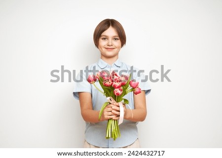 Cheerful happy child with Tulips bouquet. Smiling boy on white background. Mother's Day. Love and romantic concept