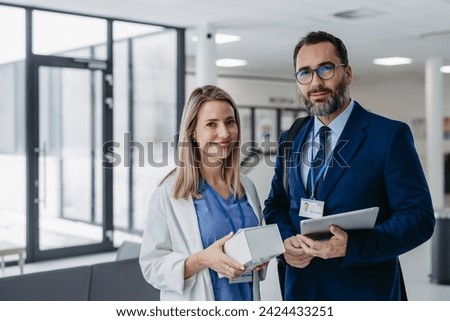Pharmaceutical sales representative talking with doctor in medical building. Ambitious male sales representative presenting new medication on tablet. Royalty-Free Stock Photo #2424433251