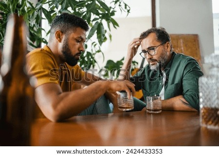 Best friends, supporting each other, drinking whiskey and talking. Discussing problems and drowning sorrows in alcohol. Concept of male friendship, bromance. Royalty-Free Stock Photo #2424433353