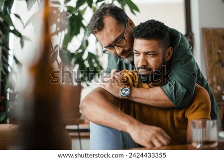 Man hugging best friend, supporting each other, drinking whiskey and talking. Discussing problems and drowning sorrows in alcohol. Concept of male friendship, bromance. Royalty-Free Stock Photo #2424433355