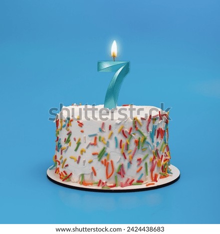 7 shaped candle light on happy birthday cake on blue