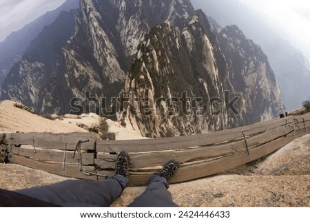 Hua Shan mountains in China. High cliff plank walk. Hiking up the mountain. Abyss trail. Dangerous climbing. Famous walk at the edge. Wooden path over abyss. Xian city in China. Royalty-Free Stock Photo #2424446433