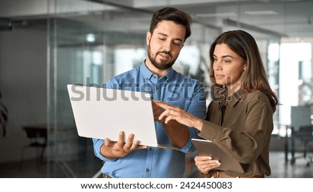 Two busy professional business people working in office with computer. Middle aged female executive manager talking to male colleague having conversation showing software online solution on laptop. Royalty-Free Stock Photo #2424450083