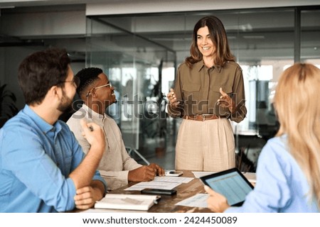 Happy middle aged business woman executive ceo leader discussing project management planning strategy working with diverse colleagues company team at office corporate board group meeting. Royalty-Free Stock Photo #2424450089