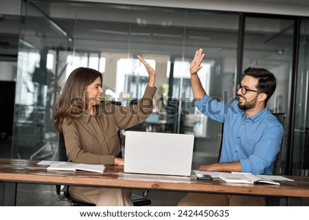 Happy excited executive business team two partners employees giving high five supporting celebrating professional success growth or financial work achievement sitting at office meeting with laptop. Royalty-Free Stock Photo #2424450635