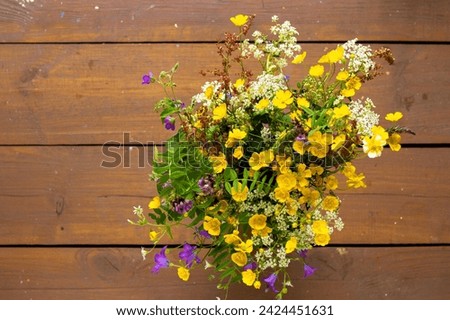 Bright colorful bouquet of wild flowers standing on wooden background with copy space, horizontal rustic floral photo