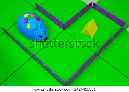 Toy mouse goes for cheese in maze. Modern electric toy on the playing field, teaching children technologies through games