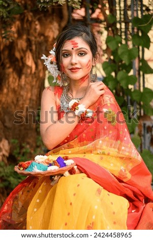 Portrait of pretty young girl wearing traditional Indian saree and jewellery, holding powder colours in plate on the festival of colours called Holi, a popular Hindu festival celebrated across India. Royalty-Free Stock Photo #2424458965