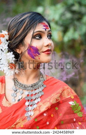Portrait of pretty young girl wearing traditional Indian saree and jewellery, playing with colours on the festival of colours called Holi, a popular hindu festival celebrated across India. Royalty-Free Stock Photo #2424458969