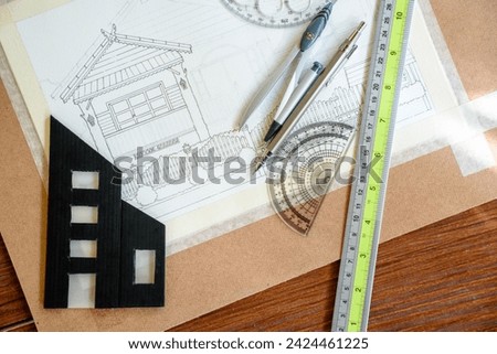 Top-view of architectural plans for building a house and miniature building models for engineering design or blueprints with tools like a pencil and ruler for sketching or drawing.