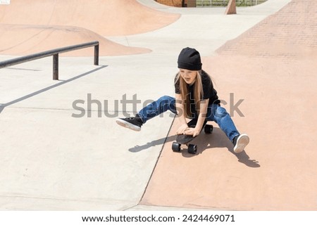 Pretty happy little girl riding on skateboard in skate park in summer day
