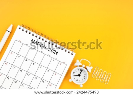 March 2024, Monthly desk calendar for 2024 year and alarm clock with paper clips on yellow color background. Position with copy space. Royalty-Free Stock Photo #2424475493