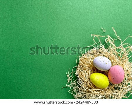 Happy Easter postcard. Colored Easter eggs in nest on green background, image with selective focus, top view
