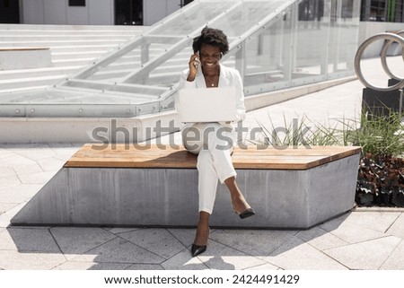 beautiful african female with laptop is calling by phone