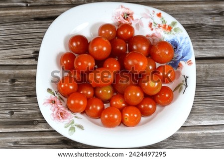 The cherry tomato, a type of small round tomato believed to be an intermediate genetic admixture between wild currant-type tomatoes and domesticated garden tomatoes, Cherry tomatoes range in size Royalty-Free Stock Photo #2424497295