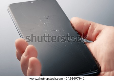Smartphone with a broken screen in a man's hand.