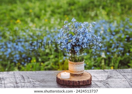 Bouquet of blue blossom wild flowers Myosotis also known as Forget me not or scorpion grasses in decorated mason jar. Beautiful vintage floral still life. Royalty-Free Stock Photo #2424513737