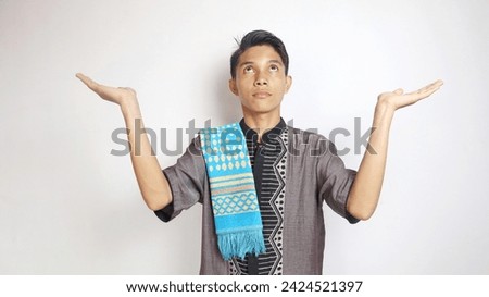 asian muslim man opens arms wide and looks up against white background