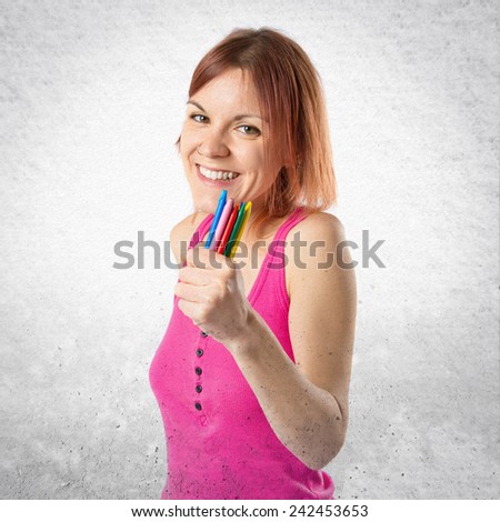 Young redhead girl holding crayons over textured background