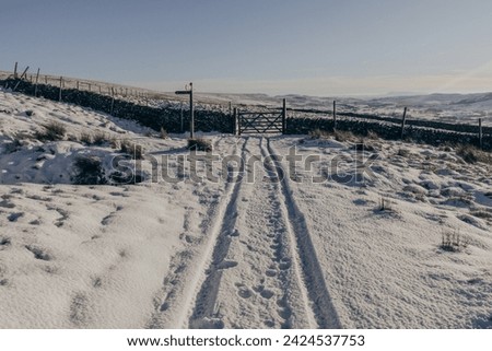 A wooden signpost, a gate, a drystone wall and tracks in the snow in the Yorkshire Dales National Park between Ribblehead and Horton-in-Ribblesdale.

Taken on a beautiful winter day. Royalty-Free Stock Photo #2424537753