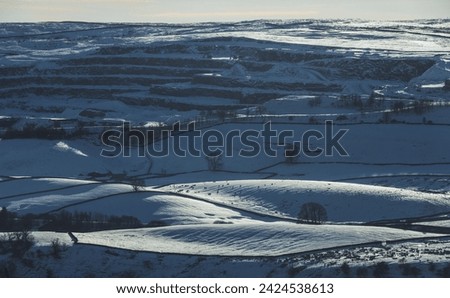 Dramatic view of the quarry above Horton-in-Ribblesdale in the Yorkshire Dales National Park on a beautiful winter day with bright sunshine and lots of snow on the ground. Royalty-Free Stock Photo #2424538613