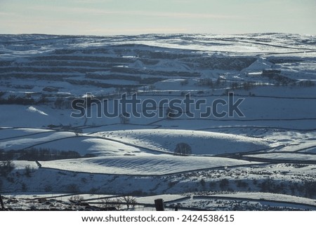 Dramatic view of the quarry above Horton-in-Ribblesdale in the Yorkshire Dales National Park on a beautiful winter day with bright sunshine and lots of snow on the ground. Royalty-Free Stock Photo #2424538615