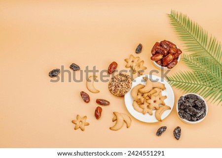 Traditional Ramadan Kareem concept snack for Iftar or Suhoor meal on light orange background. An arabian sweet treat, dates, prunes and cookies. Flat lay, top view Royalty-Free Stock Photo #2424551291