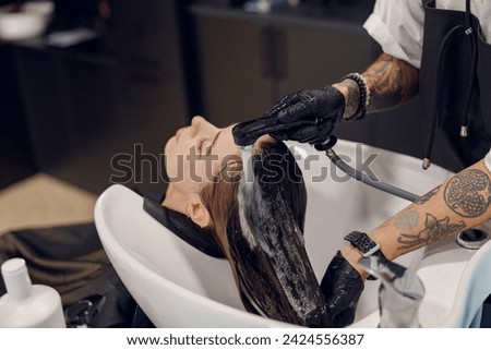Close up of hairdresser is washing hair of young woman in beauty salon. High quality photo Royalty-Free Stock Photo #2424556387