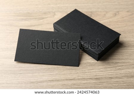 Blank black business cards on wooden table. Mockup for design