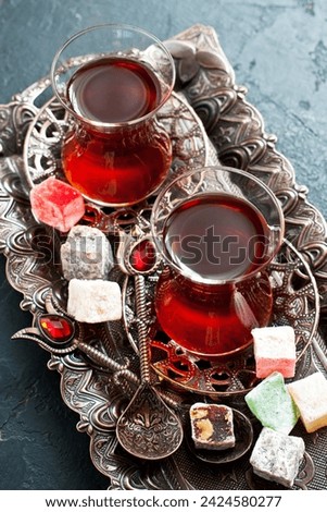 Cups of turkish tea served in traditional style with turkish delights on dark  background

