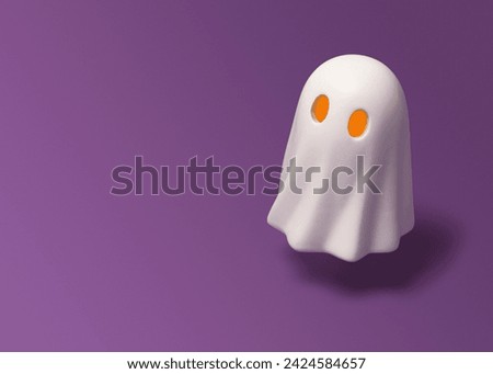 Halloween banner with ghost figurine with yellow eyes on purple background. Space for your text